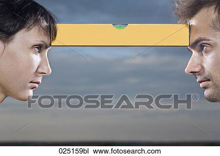 Stock Image - young woman and man face to face balancing spirit-level. Fotosearch