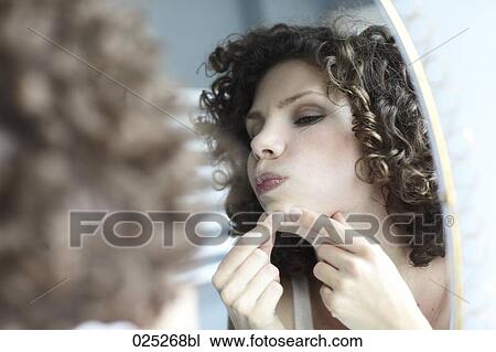 young woman checking her face in the mirror View Large Photo Image Stock Image - young woman checking her face in the mirror. Fotosearch