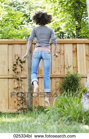 young woman in garden trying to look over the fence View Large Photo Image Stock Image - young woman in garden trying to look over the fence. Fotosearch