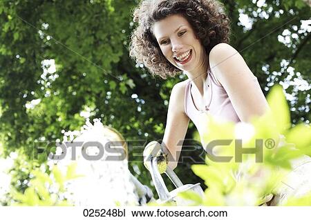 young woman in garden watering plants View Large Photo Image Stock Image - young woman in garden watering plants. Fotosearch