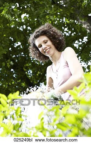 young woman in garden watering plants View Large Photo Image Stock Image - young woman in garden watering plants. Fotosearch