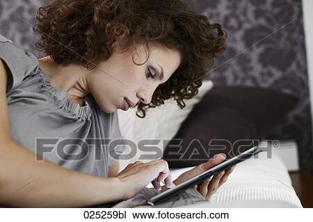 young woman lying in bed with tablet computer View Large Photo Image Stock Image - young woman lying in bed with tablet computer. Fotosearch