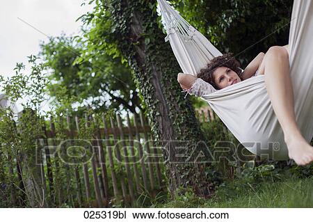 Stock Image - young woman lying in hammock in garden. Fotosearch