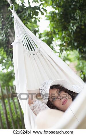Stock Image - young woman lying in hammock in garden. Fotosearch