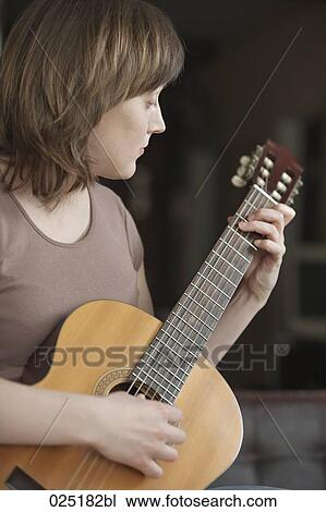 Stock Image - young woman playing guitar. Fotosearch