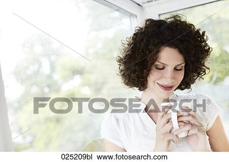 young woman standing by the window with cup of coffee View Large Photo Image Stock Image - young woman standing by the window with cup of coffee. Fotosearch