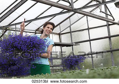 Stock Image - young woman working in greenhouse. Fotosearch