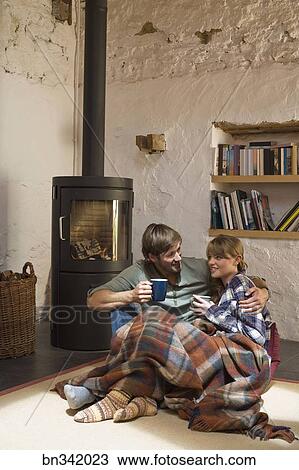Couple Snuggling By Wood Stove Indoors Stock Image Bn342023