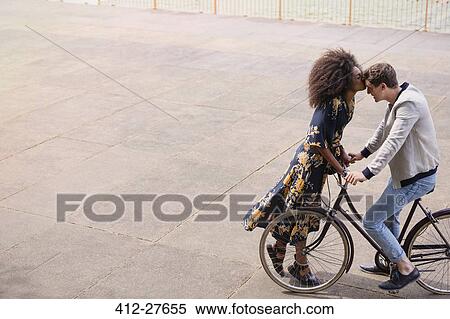 Stock Photography - Affectionate woman kissing man on bicycle. Fotosearch