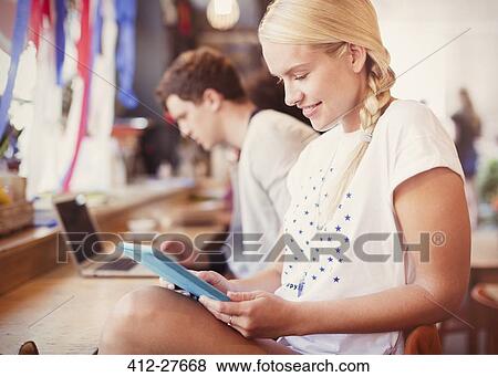 Blonde woman using digital tablet in cafe View Large Photo Image Stock Photo - Blonde woman using digital tablet in cafe. Fotosearch