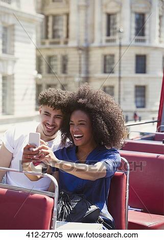 Stock Photography - Couple taking selfie on double-decker bus. Fotosearch