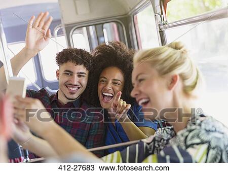 Enthusiastic friends taking selfie on bus View Large Photo Image Stock Image - Enthusiastic friends taking selfie on bus. Fotosearch