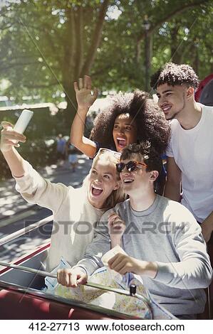 Enthusiastic friends taking selfie on double-decker bus View Large Photo Image Stock Image - Enthusiastic friends taking selfie on double-decker bus. Fotosearch
