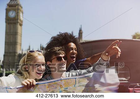 Stock Image - Enthusiastic friends with map below Big Ben clocktower in London. Fotosearch