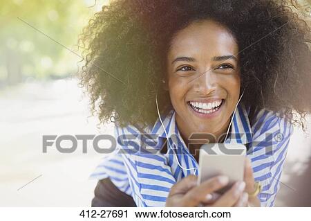 Stock Image - Enthusiastic woman listening to music with headphones and mp3 player. Fotosearch