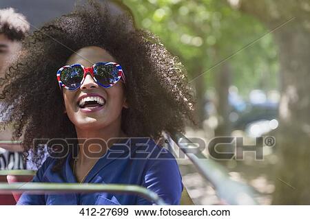 Stock Photo - Enthusiastic woman with afro wearing heart-shape glasses. Fotosearch
