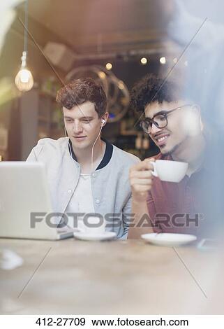 Friends drinking coffee and using laptop in cafe View Large Photo Image Stock Photo - Friends drinking coffee and using laptop in cafe. Fotosearch