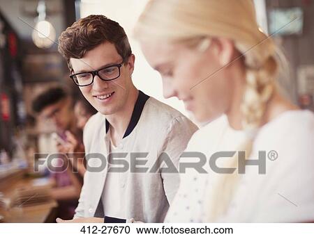 Stock Image - Friends looking down in cafe. Fotosearch