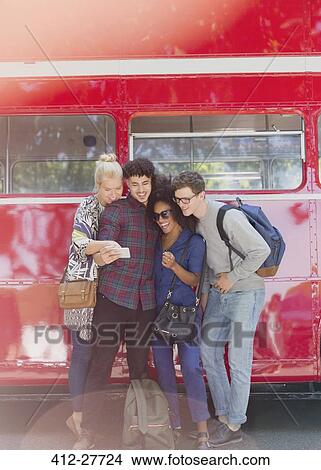 Picture - Friends taking selfie next to double-decker bus. Fotosearch