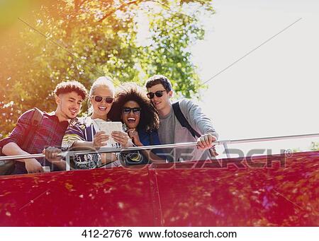 Friends taking selfie on double-decker bus View Large Photo Image Stock Photograph - Friends taking selfie on double-decker bus. Fotosearch