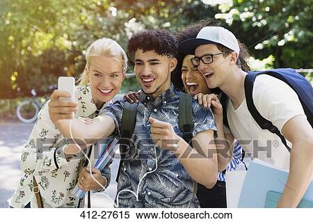 Stock Photography - Friends taking selfie with camera phone in park. Fotosearch