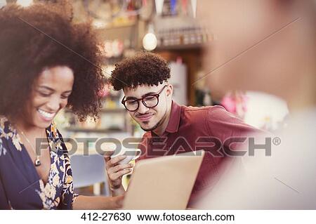Friends using laptop and drinking coffee in cafe View Large Photo Image Stock Image - Friends using laptop and drinking coffee in cafe. Fotosearch