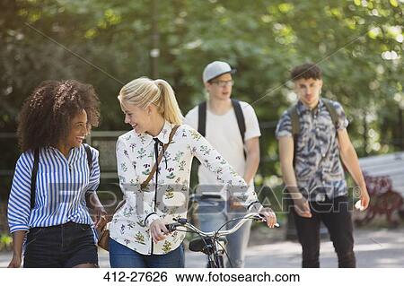 Friends walking with bicycle in park View Large Photo Image Stock Photograph - Friends walking with bicycle in park. Fotosearch