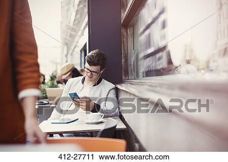 Man listening to headphones with mp3 player at sidewalk cafe View Large Photo Image Stock Image - Man listening to headphones with mp3 player at sidewalk cafe. Fotosearch