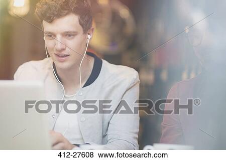 Man listening to music on headphones and using laptop View Large Photo Image Stock Photo - Man listening to music on headphones and using laptop. Fotosearch