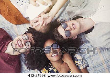 Overhead portrait smiling friends laying in circle on blanket View Large Photo Image Stock Photo - Overhead portrait smiling friends laying in circle on blanket. Fotosearch