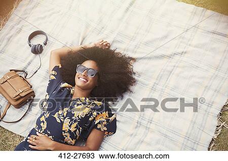 Overhead view smiling woman with afro laying on blanket outdoors View Large Photo Image Stock Image - Overhead view smiling woman with afro laying on blanket outdoors. Fotosearch