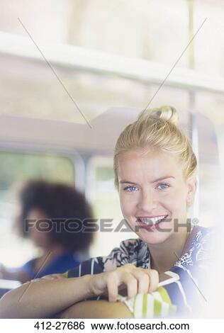 Stock Photograph - Portrait smiling blonde woman holding cell phone on bus. Fotosearch