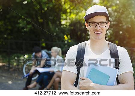 Stock Image - Portrait smiling college student with books in park. Fotosearch