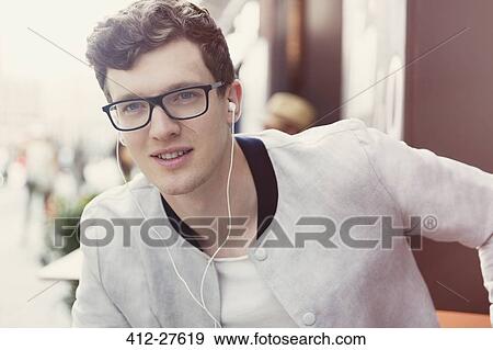 Stock Photo - Portrait smiling man with eyeglasses listening to music on headphones. Fotosearch