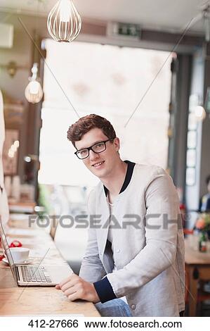 Portrait smiling man with eyeglasses using laptop in cafe View Large Photo Image Stock Photograph - Portrait smiling man with eyeglasses using laptop in cafe. Fotosearch