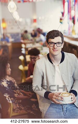 Stock Photography - Portrait smiling man with eyeglasses drinking cappuccino in cafe. Fotosearch