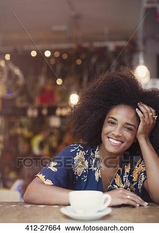 Picture - Portrait smiling woman with afro drinking coffee in cafe. Fotosearch