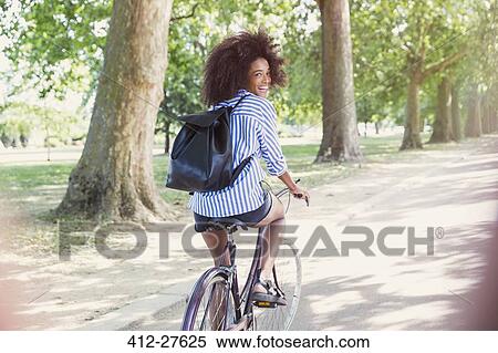 Portrait smiling woman with afro riding bicycle in park View Large Photo Image Stock Photography - Portrait smiling woman with afro riding bicycle in park. Fotosearch