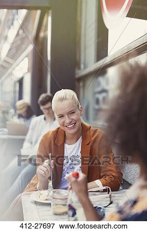 Stock Photo - Smiling friends eating dessert at sidewalk cafe. Fotosearch