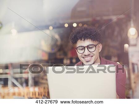 Smiling man with curly black hair using laptop at cafe window View Large Photo Image Stock Photo - Smiling man with curly black hair using laptop at cafe window. Fotosearch