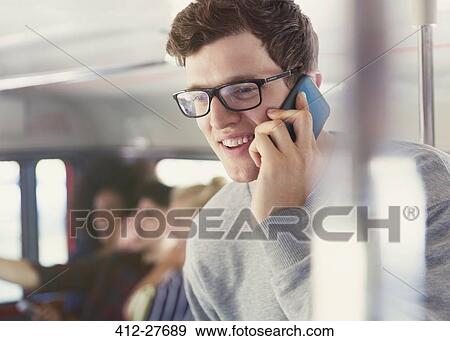 Smiling man with eyeglasses talking on cell phone on bus View Large Photo Image Stock Photo - Smiling man with eyeglasses talking on cell phone on bus. Fotosearch