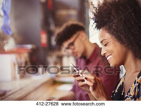 Stock Photo - Smiling woman texting with cell phone. Fotosearch