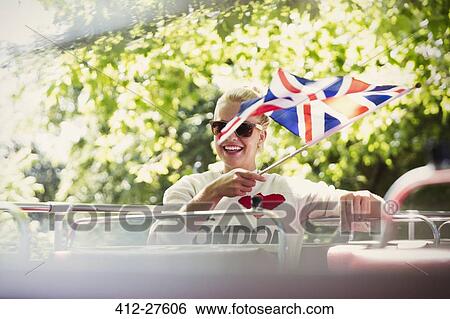 Smiling woman waving British flag on double-decker bus View Large Photo Image Stock Photograph - Smiling woman waving British flag on double-decker bus. Fotosearch