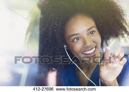 Stock Photograph - Smiling woman with afro and headphones drawing heart-shape on bus window. Fotosearch