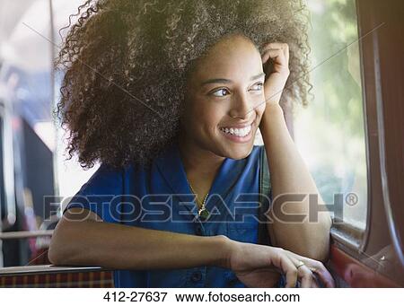 Smiling woman with afro riding bus looking out window View Large Photo Image Stock Photo - Smiling woman with afro riding bus looking out window. Fotosearch