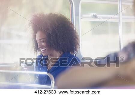 Smiling woman with afro texting with cell phone on bus View Large Photo Image Stock Image - Smiling woman with afro texting with cell phone on bus. Fotosearch