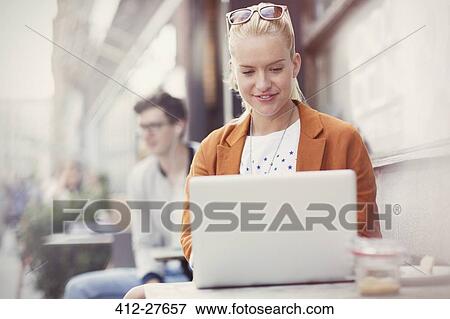 Stock Photo - Woman using laptop at sidewalk cafe. Fotosearch