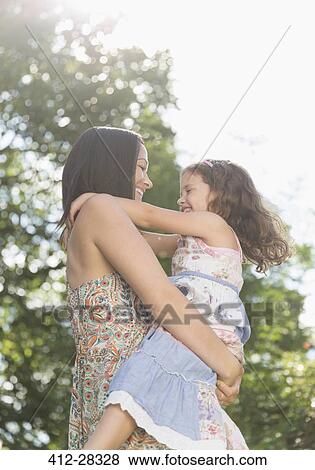 Stock Photo - Affectionate mother holding and hugging daughter outdoors. Fotosearch