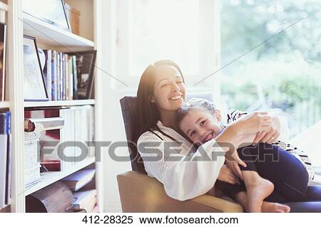 Affectionate mother hugging daughter in armchair View Large Photo Image Stock Photography - Affectionate mother hugging daughter in armchair. Fotosearch
