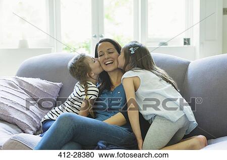 Daughters kissing mother’s cheeks on living room sofa View Large Photo Image Stock Image - Daughters kissing mother’s cheeks on living room sofa. Fotosearch